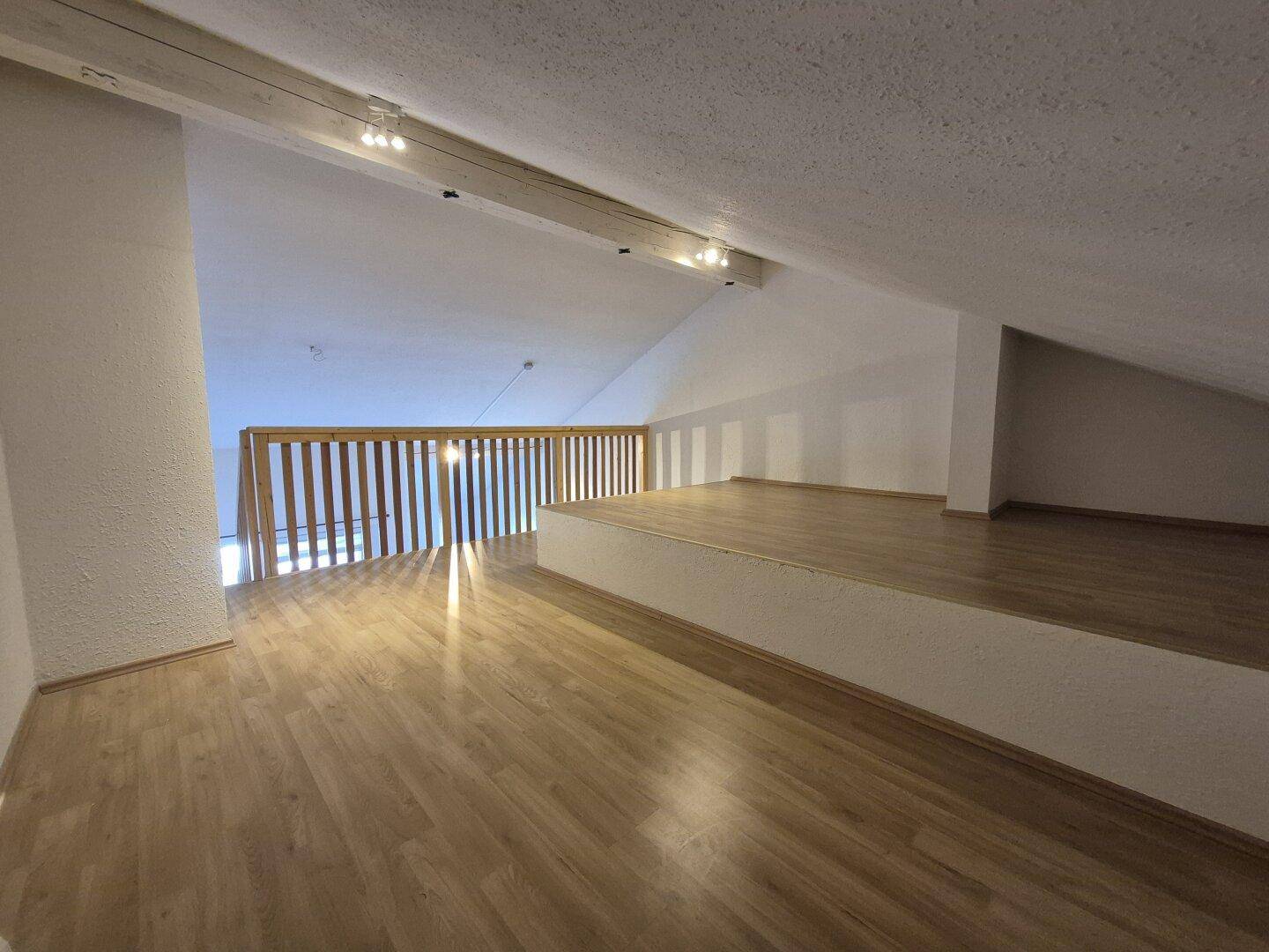 Offener Galeriebereich im Dachgeschoss mit Laminatboden und Holzgeländer.