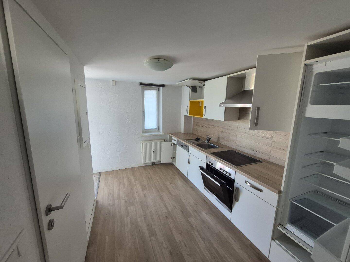 Moderne Einbauküche mit weißen Schränken, Holztheke und integrierten Geräten.