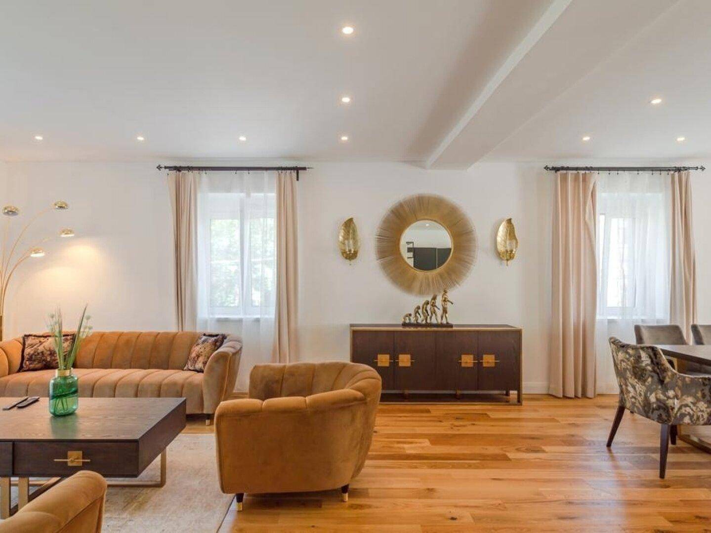 Helles Wohnzimmer mit Holzboden, stilvollen Möbeln und indirekter Beleuchtung.