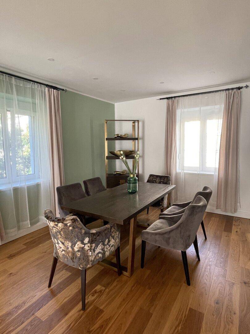 Eleganter Essbereich mit Holzboden, großem Esstisch und viel Tageslicht.