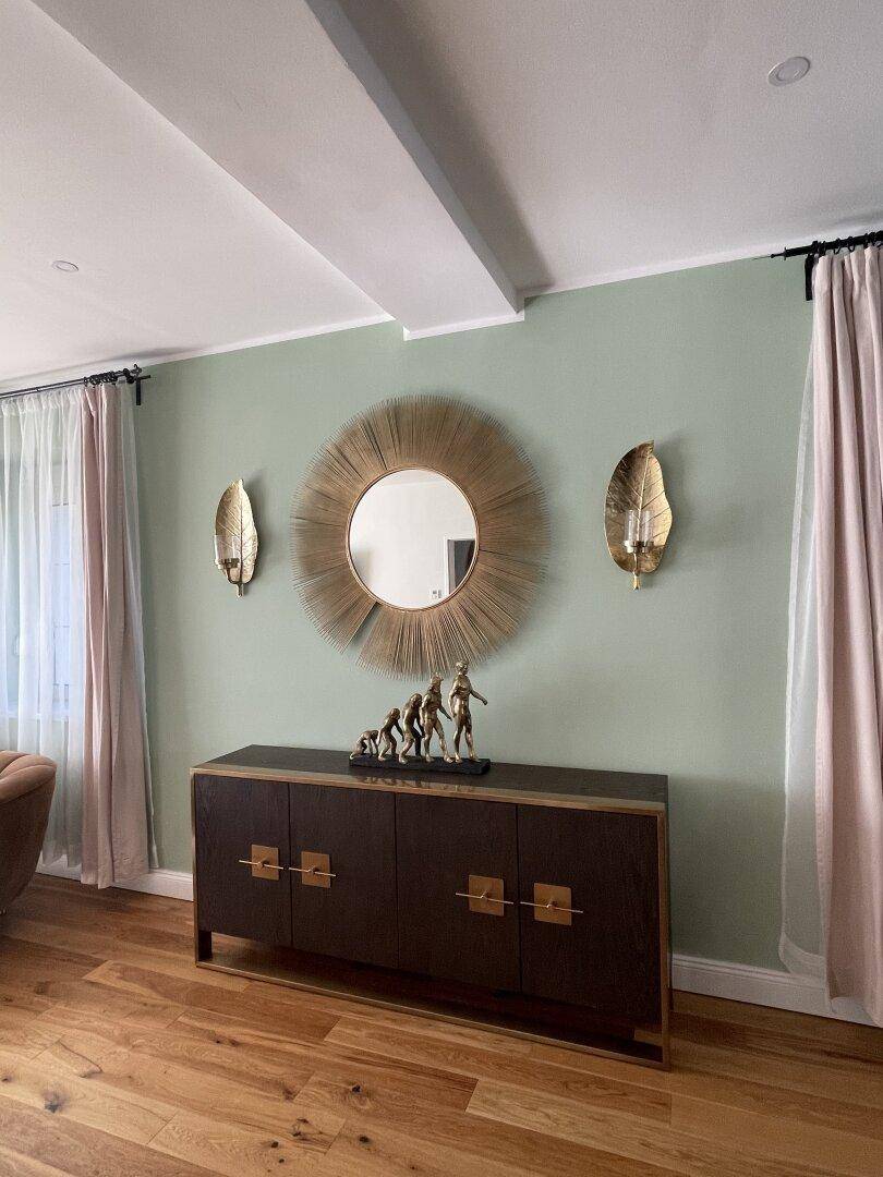Stilvolles Sideboard mit Dekoration und großem runden Spiegel im Wohnbereich.