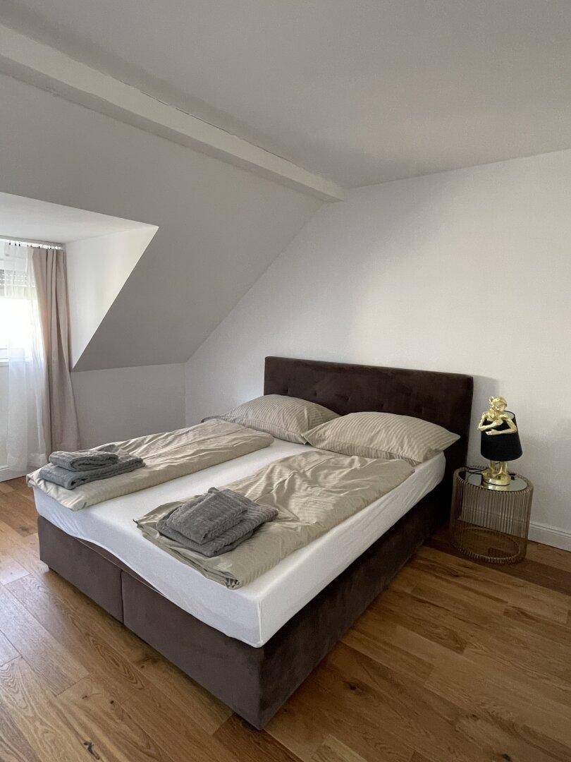 Gemütliches Schlafzimmer im Dachgeschoss mit Holzboden und Doppelbett.