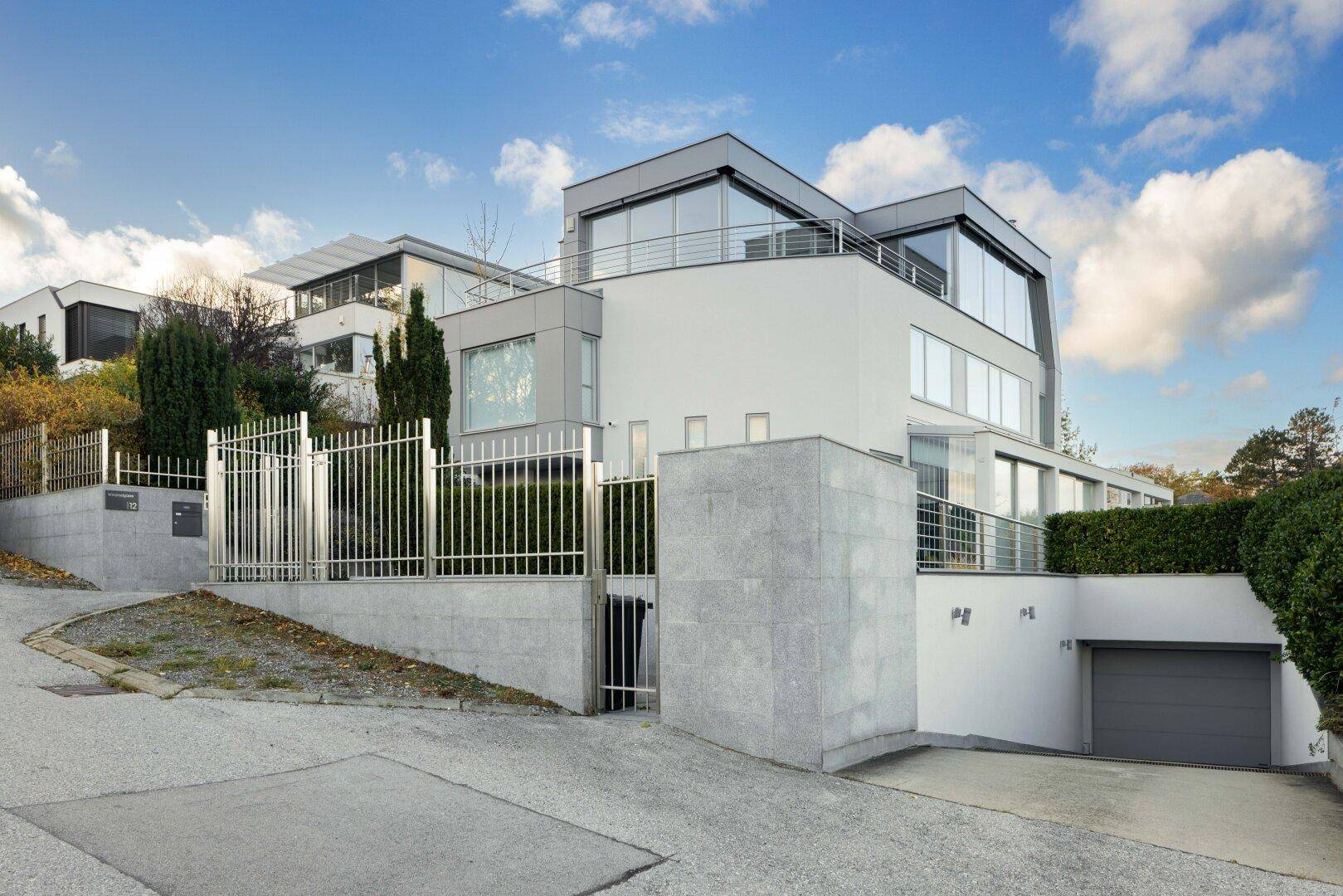 Moderne Villa mit eleganter Architektur, großen Fenstern und integrierter Tiefgarage.