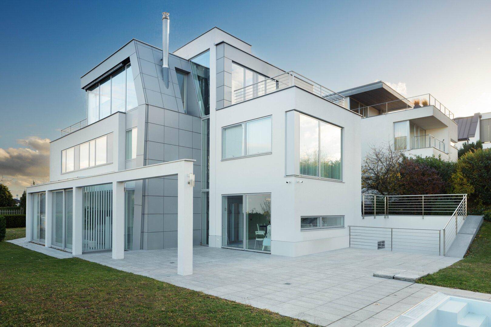 Seitliche Ansicht der modernen Villa mit weitläufiger Terrasse und gepflegtem Gartenbereich.