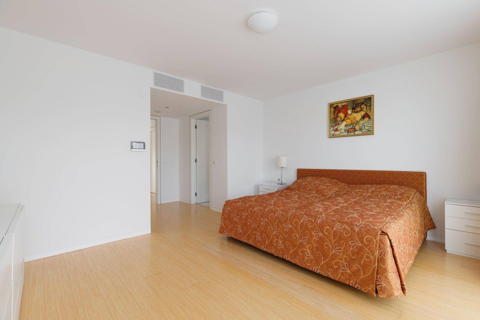 Geräumiges Schlafzimmer mit hellem Holzboden und schlichter, moderner Einrichtung.