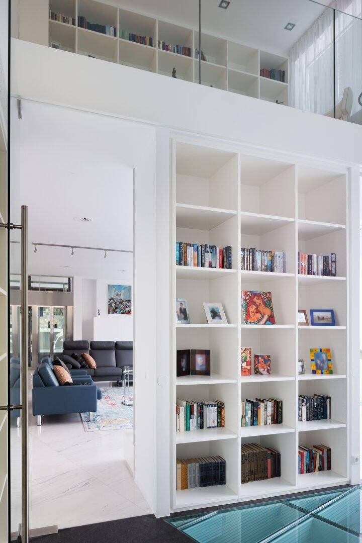 Eingangsbereich mit hohen, integrierten Bücherregalen und Blick in den Wohnbereich.