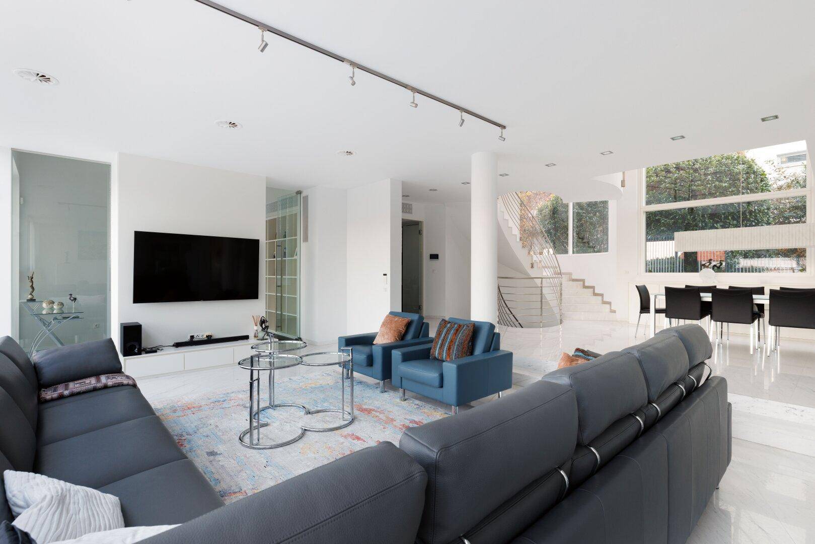 Geräumiges Wohnzimmer mit bequemen Sofas, Marmorboden und Blick auf die Wendeltreppe.