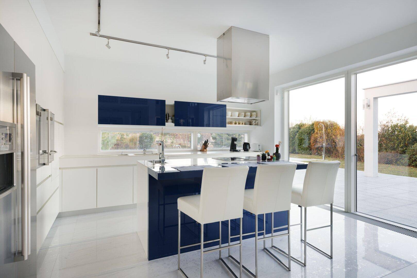 Moderne Küche mit blauen und weißen Hochglanzfronten, Kücheninsel und Terrassenzugang.