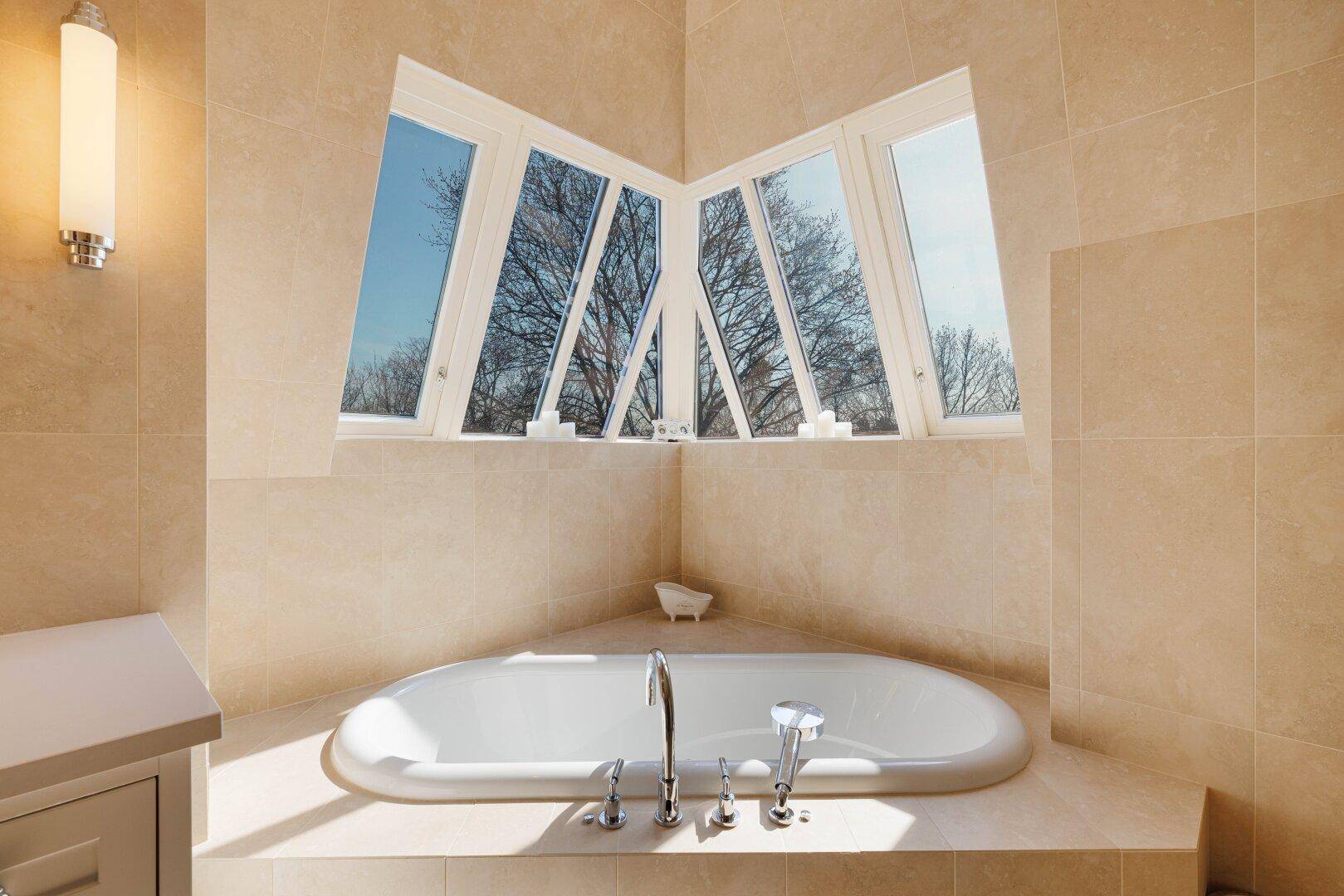Modernes Badezimmer mit eingebauter Badewanne und großen Fenstern für viel Tageslicht.