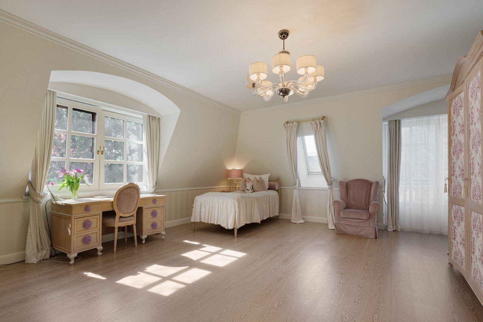 Geräumiges Schlafzimmer mit Holzboden, Schreibtisch und Fenster mit Blick ins Grüne.