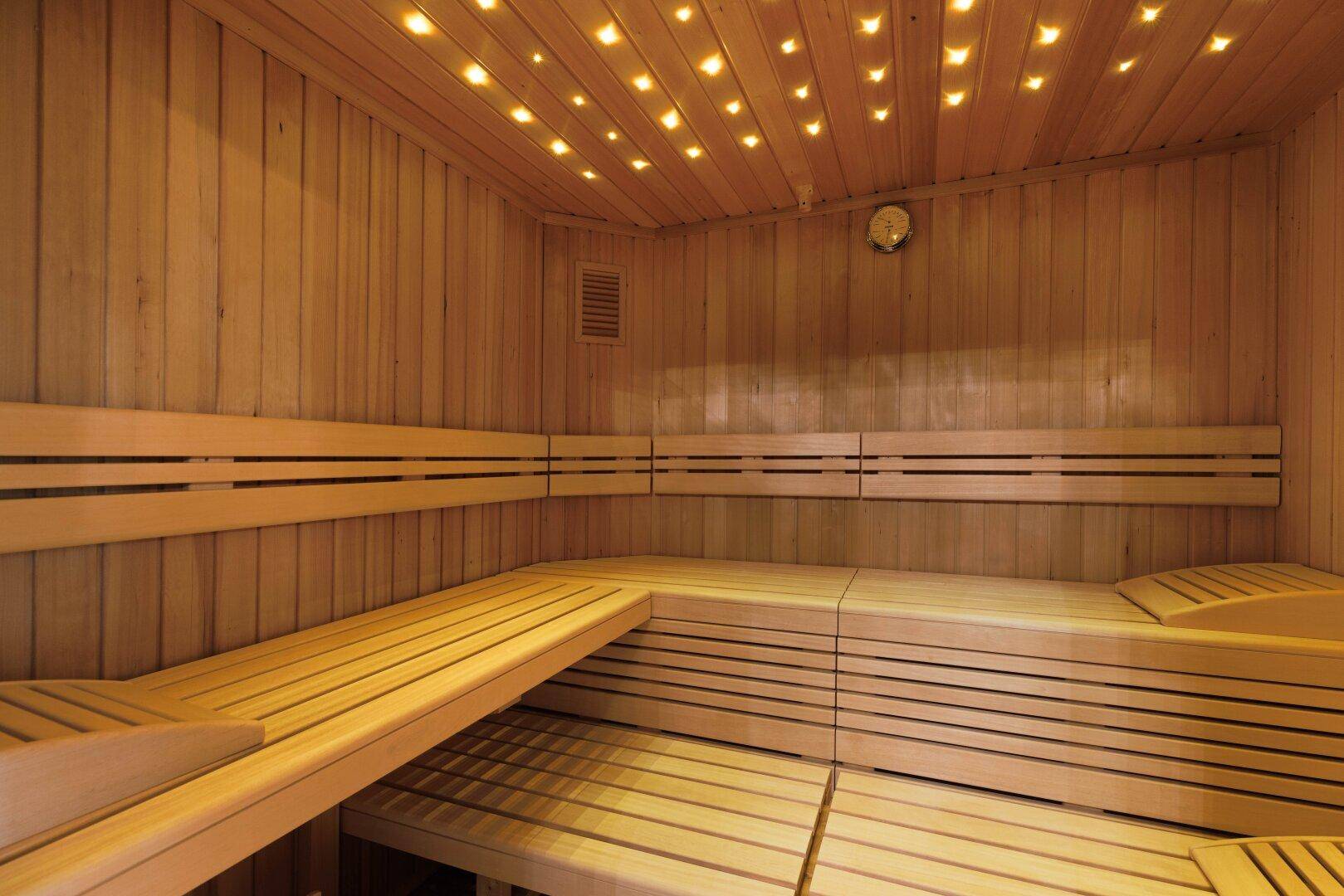 Moderne Holzsauna mit mehreren Bänken und stimmungsvoller Beleuchtung an der Decke.