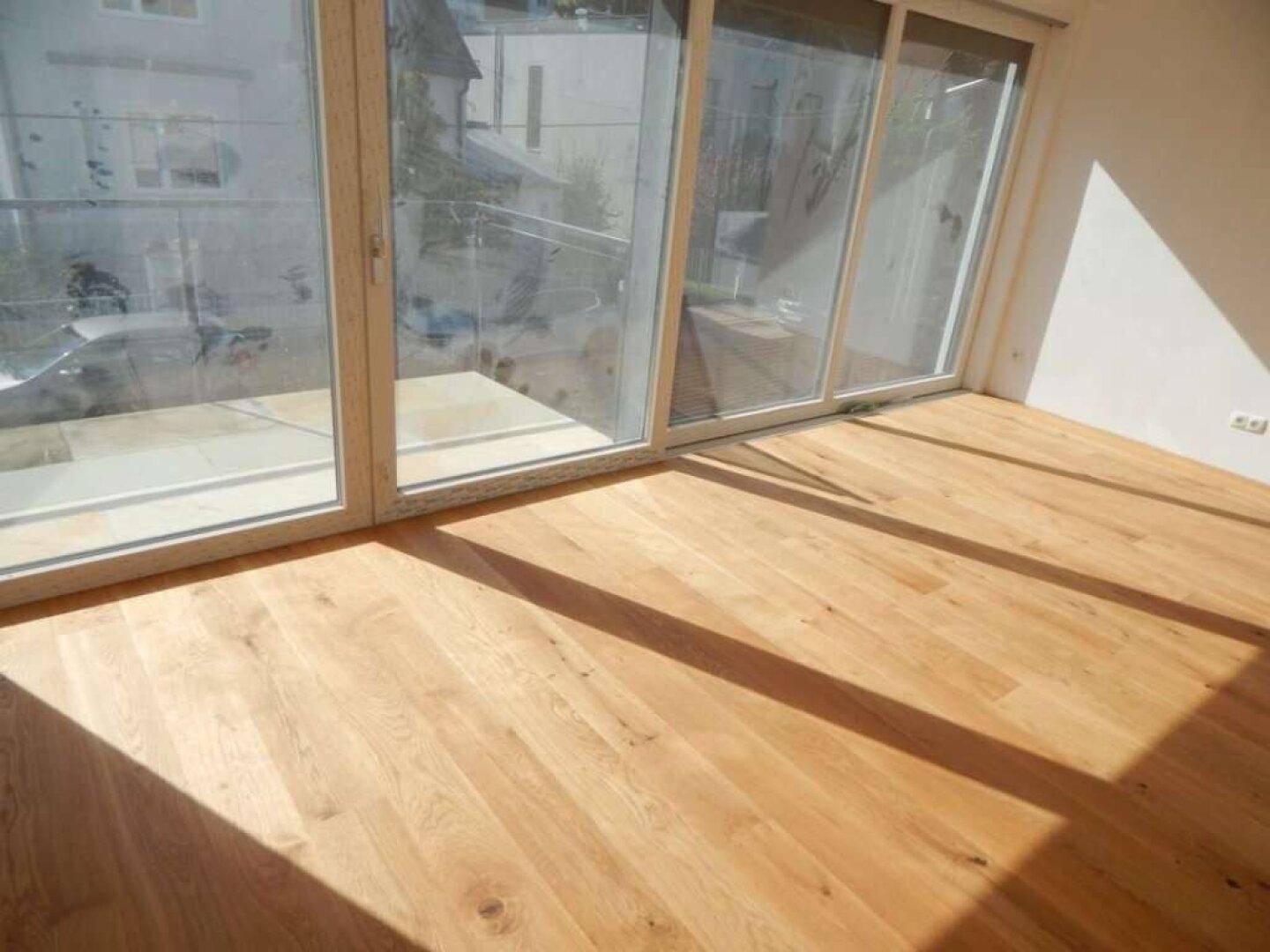 Lichtdurchfluteter Raum mit breiten Schiebetüren und hellem Holzboden, der viel Sonnenlicht einfängt.