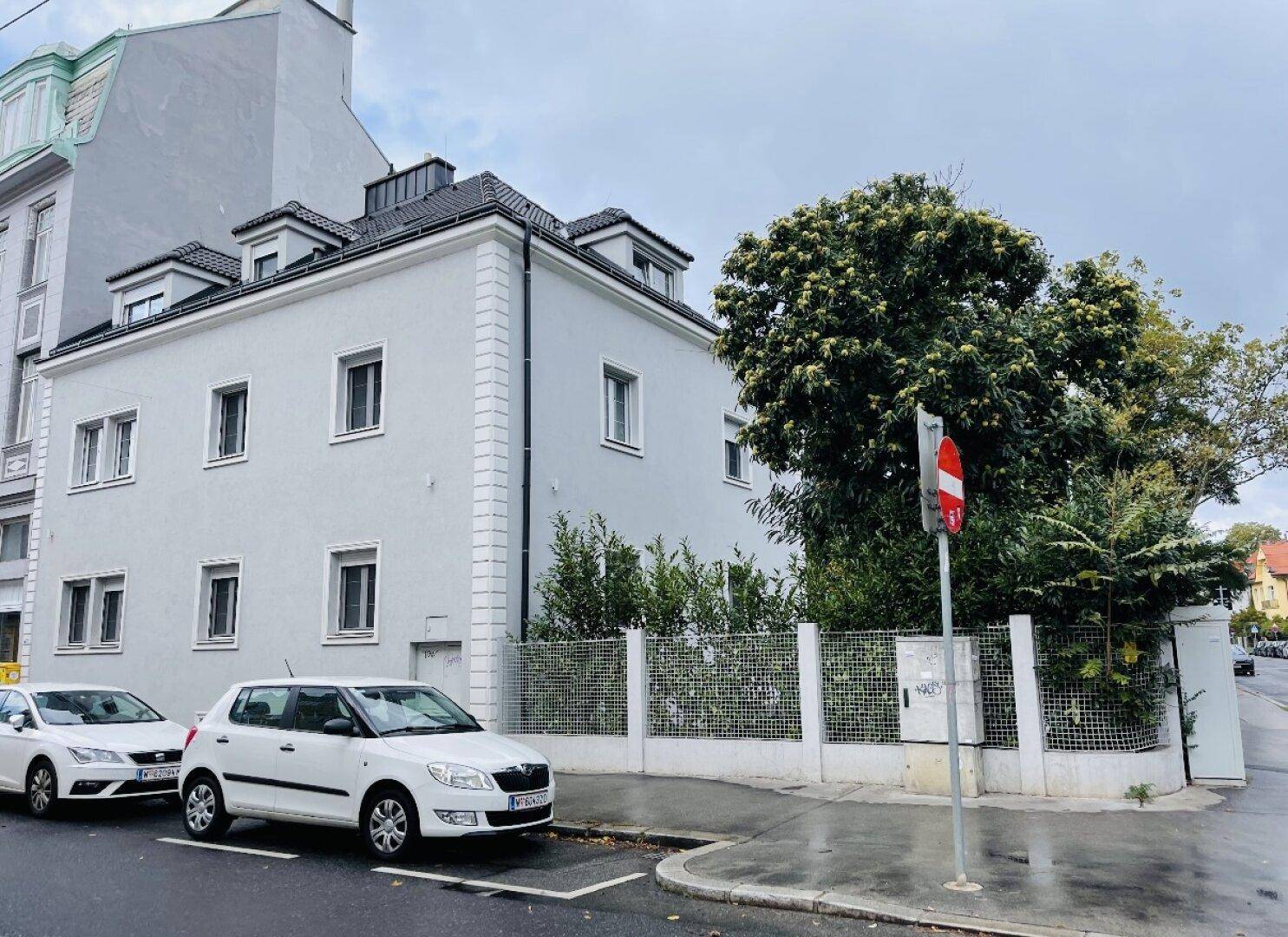 Außenansicht der Villa von der Straße aus mit parkenden Autos.