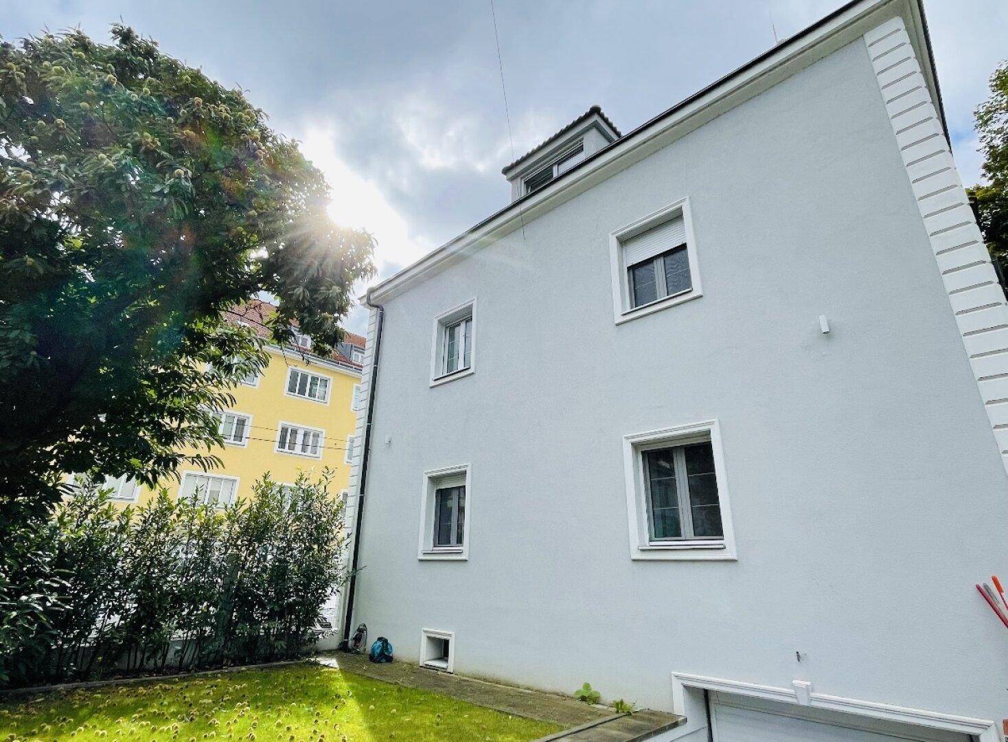 Seitenansicht der Villa mit gepflegtem Rasen und viel Grün.