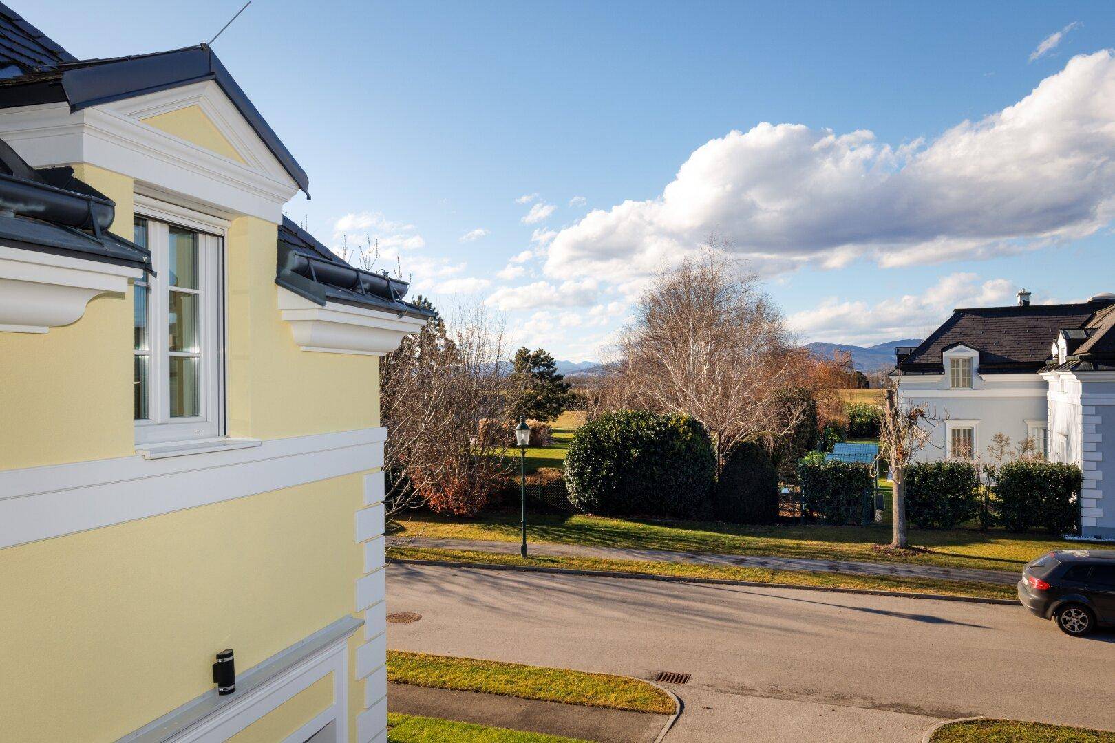 Blick vom Haus auf die Straße und die umliegende Landschaft mit Bergen im Hintergrund.