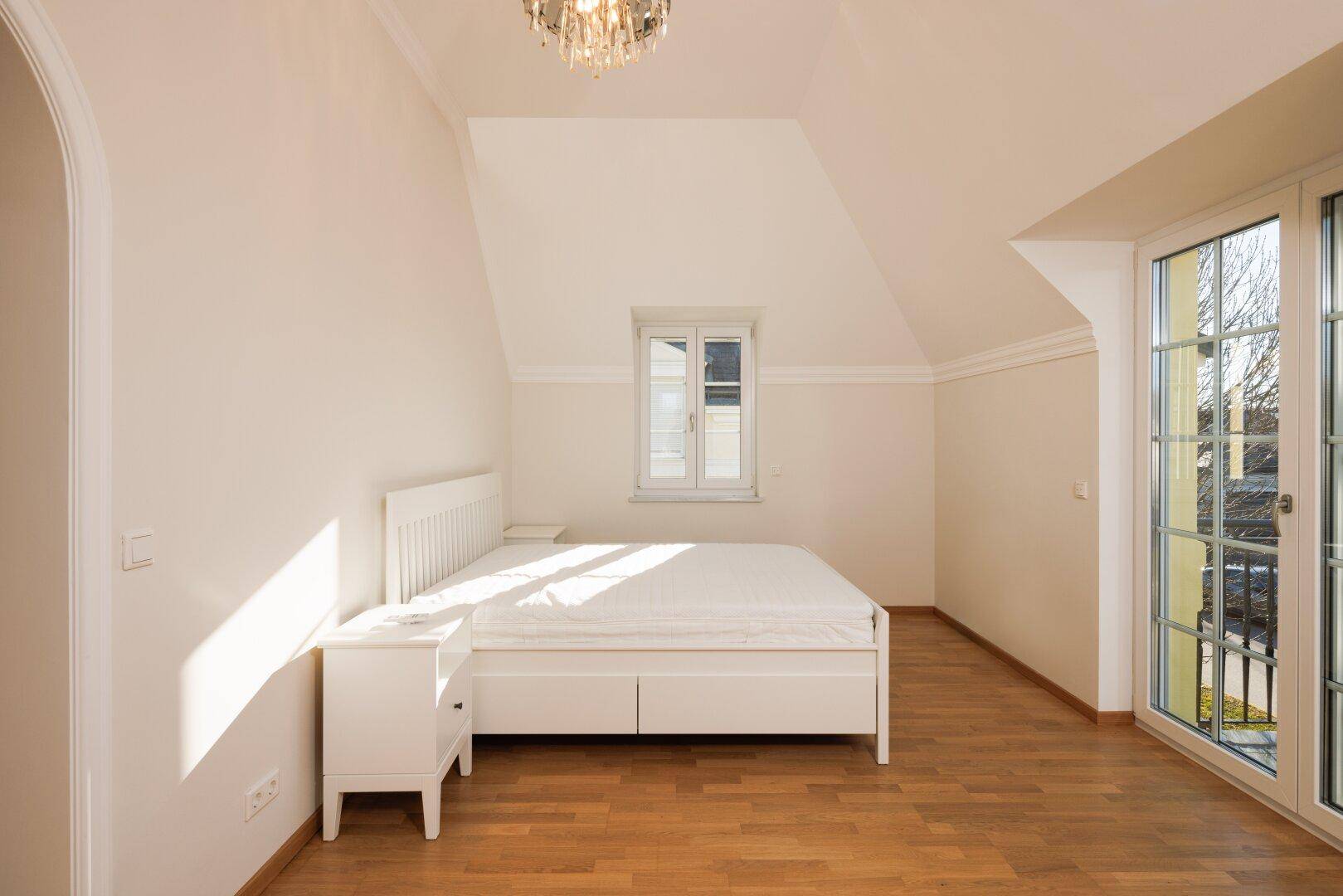 Gemütliches Schlafzimmer mit Holzboden, Dachschräge und viel natürlichem Licht.