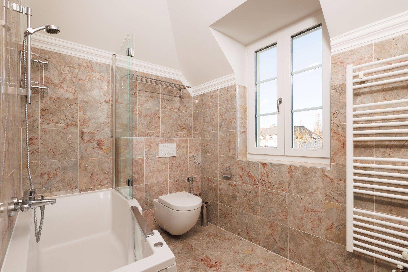 Badezimmer mit Badewanne, Dusche, WC und beheiztem Handtuchhalter.