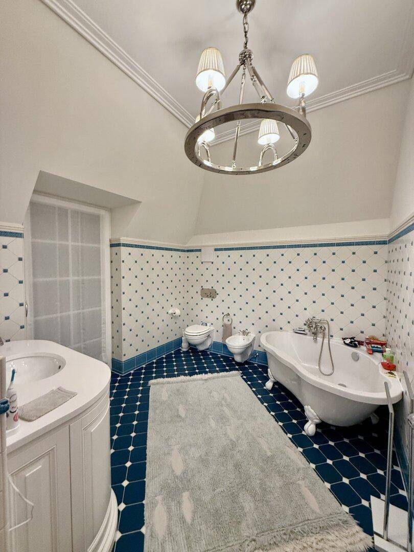 Klassisches Badezimmer mit freistehender Badewanne, Bidet und blauen Fliesen.