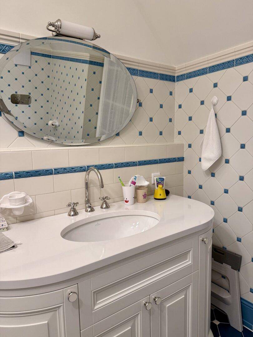 Detailansicht des Badezimmers mit Waschbecken, Spiegel und blauen Fliesen.