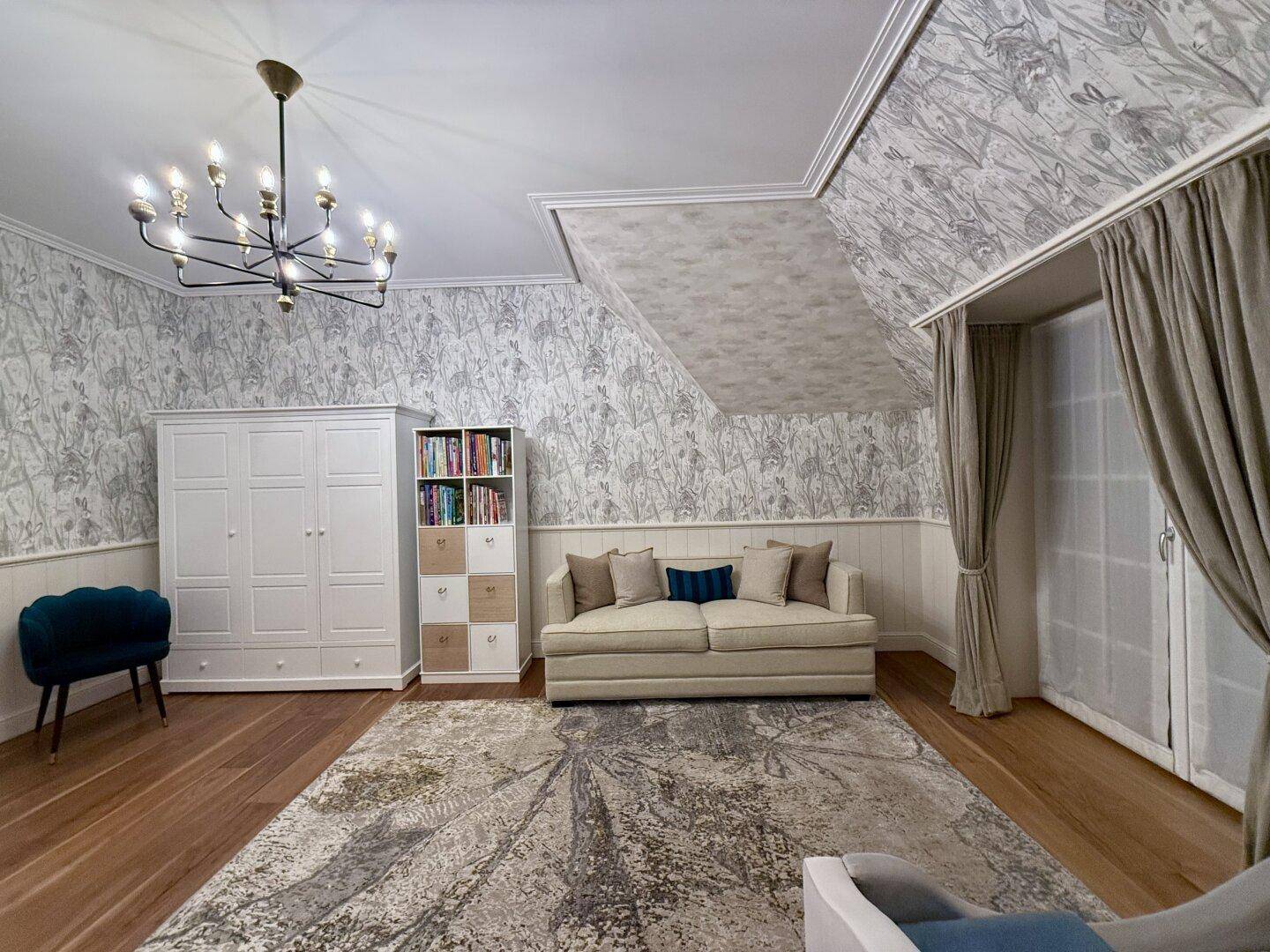 Geräumiges Zimmer mit gemusterter Tapete, Sofa und Bücherregal.