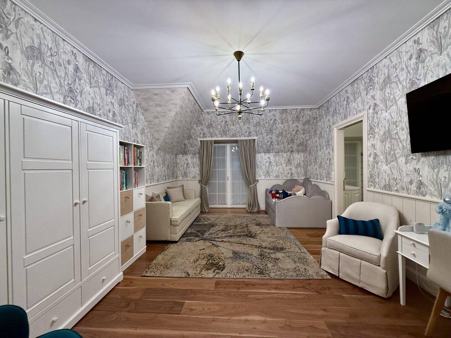 Kinderfreundliches Zimmer mit Sofa, Schrank und gemusterter Tapete.
