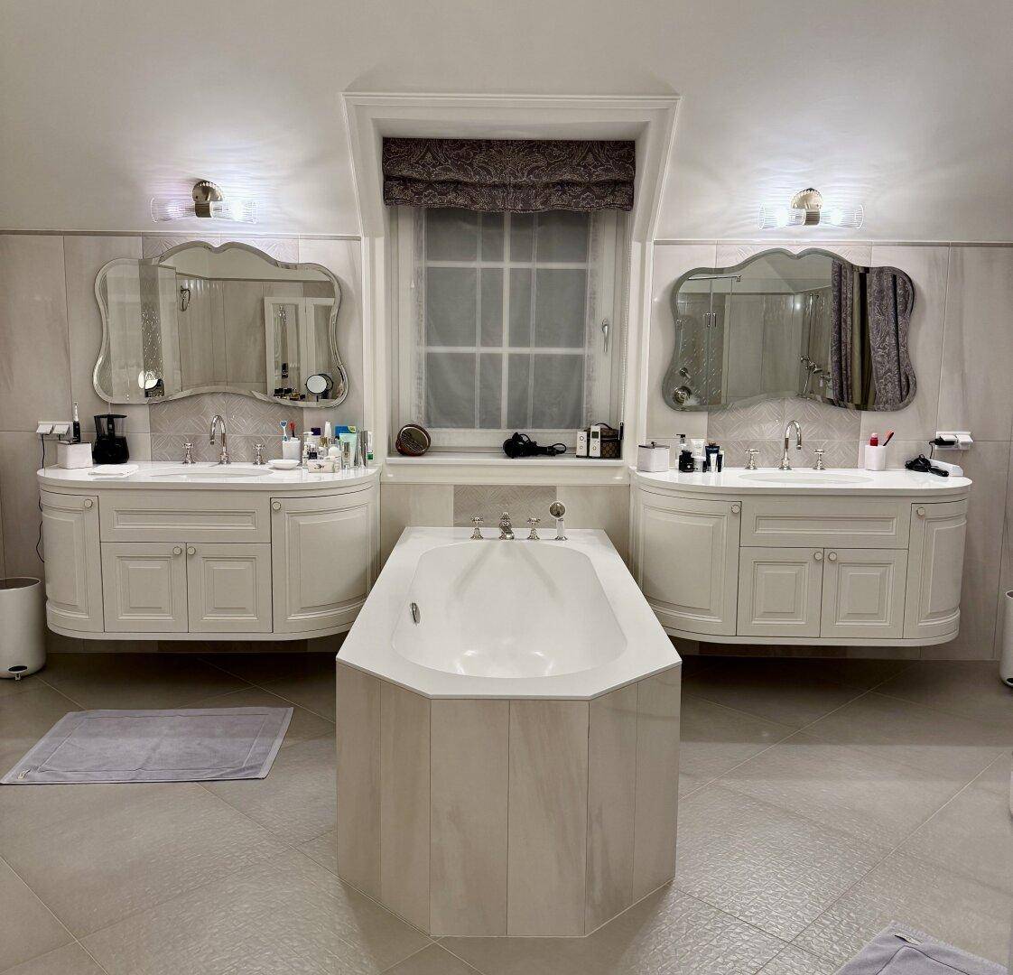Luxuriöses Badezimmer mit Doppelwaschbecken, großer Badewanne und Fenster.