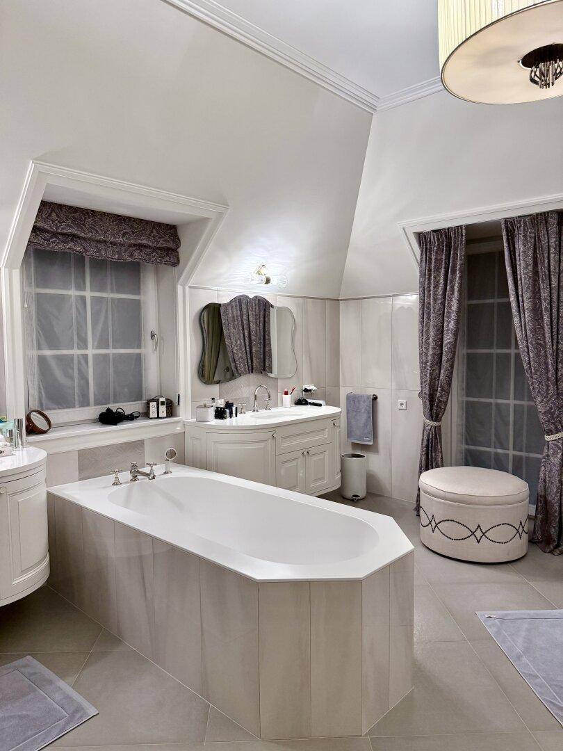 Elegantes Badezimmer mit Badewanne, Doppelwaschbecken und stilvollen Vorhängen.