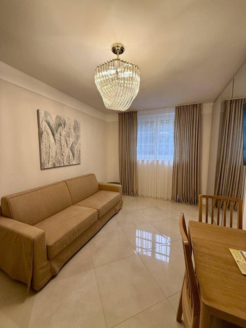 Gemütlicher Wohnbereich mit Sofa, Esstisch und elegantem Kronleuchter.