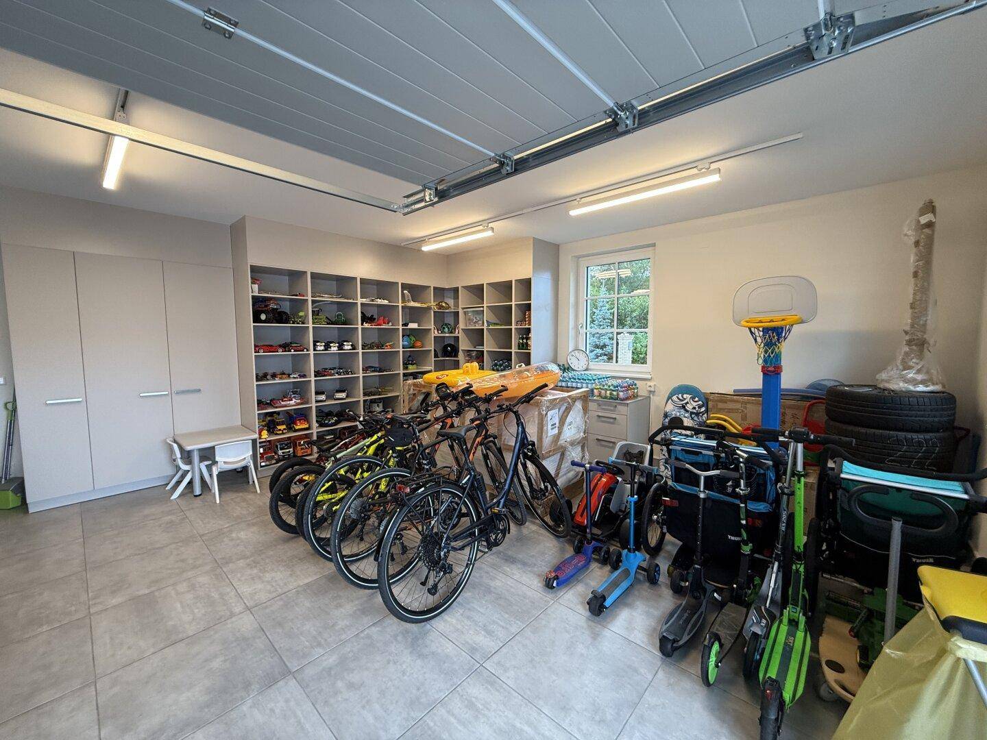 Geräumige Garage mit Fahrrädern, Spielzeug und Regalen für Lagerung.