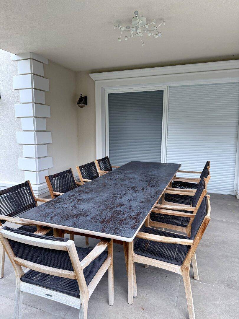 Detailansicht des großen Esstisches auf der überdachten Terrasse mit Blick ins Grüne.