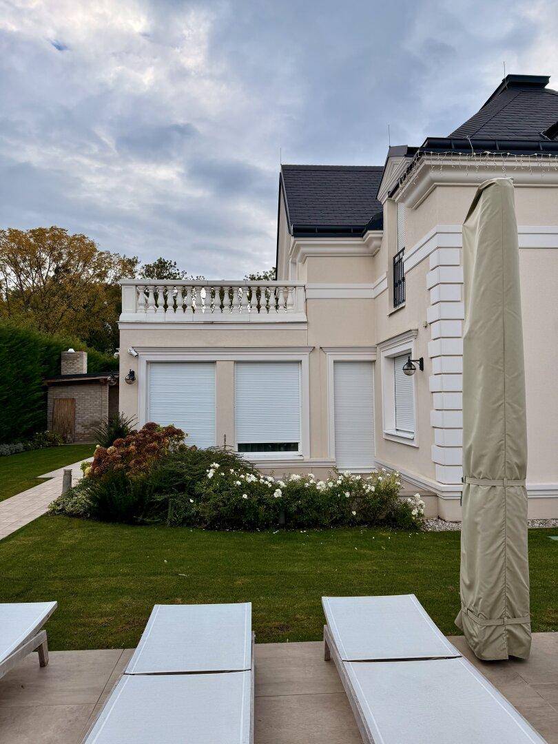 Gepflegter Gartenbereich mit Liegestühlen und Blick auf die elegante Villenfassade.