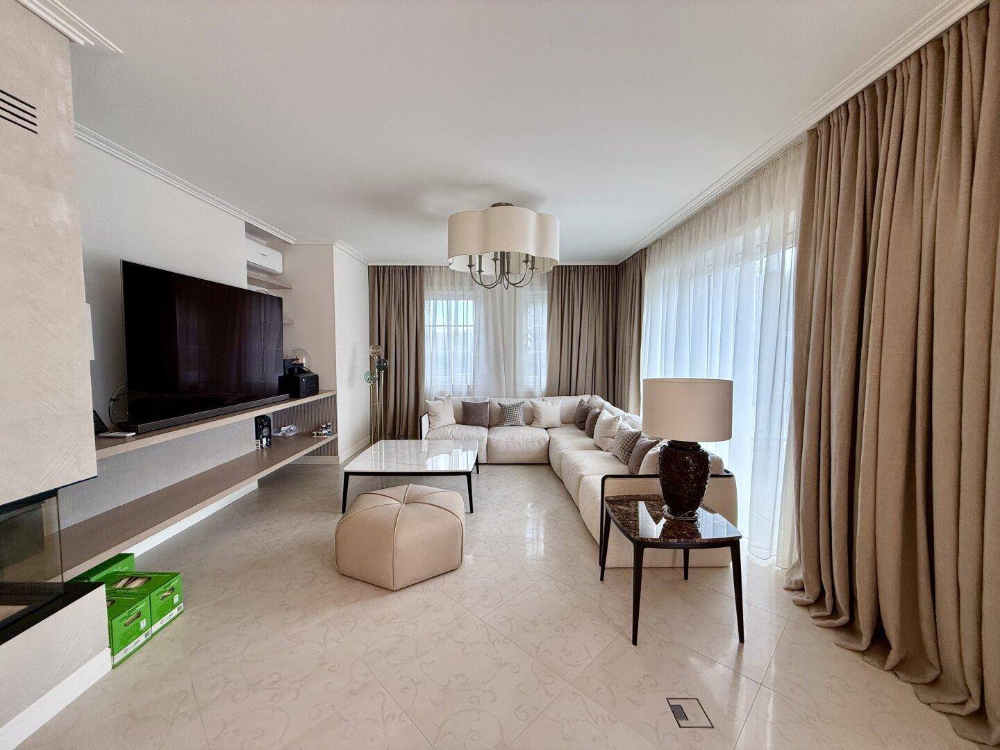 Modernes Wohnzimmer mit großem Sofa, Fernseher und Kamin.