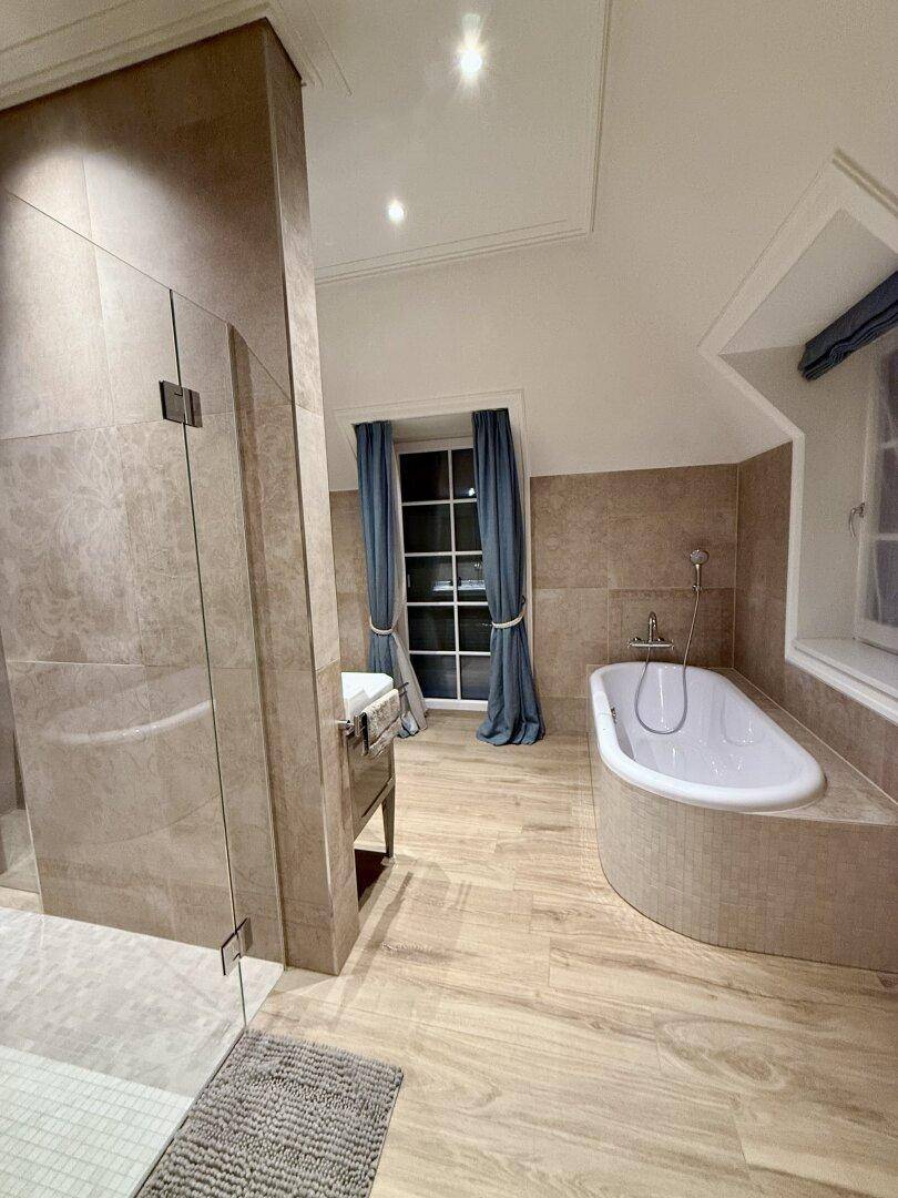 Modernes Badezimmer mit Badewanne, Duschkabine und Holzoptik-Fliesen.