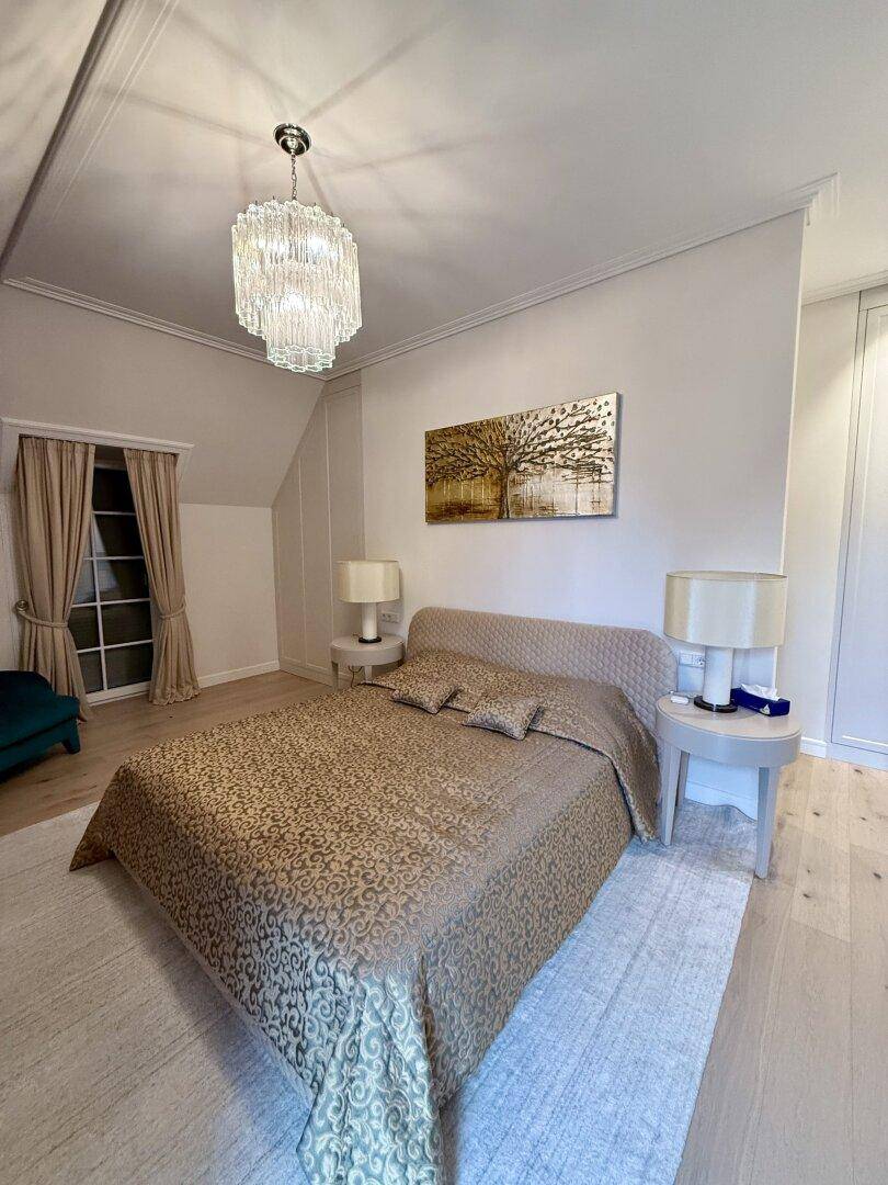 Elegantes Schlafzimmer mit großem Bett, Teppich und stilvollem Kronleuchter.