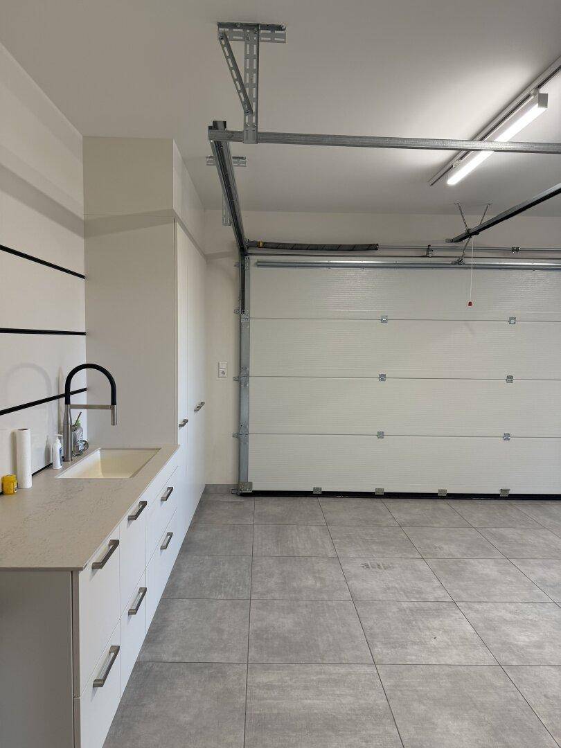 Geräumige Garage mit Rolltor, Waschbecken und viel Platz.