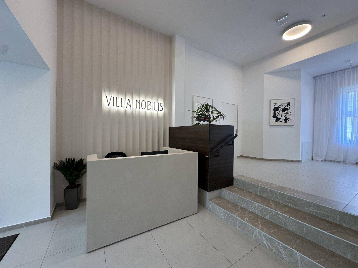 Heller und einladender Empfangsbereich mit Rezeption und dem Schriftzug "Villa Nobilis".