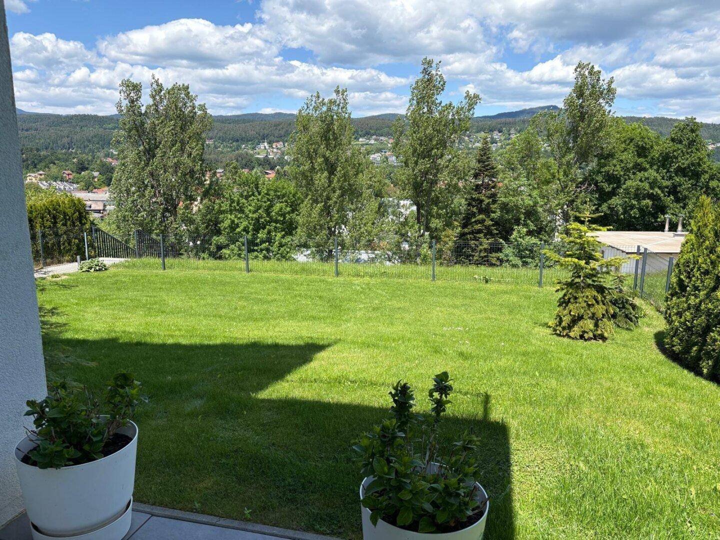 Gepflegte Rasenfläche mit Blick auf Bäume und die umliegende Landschaft.