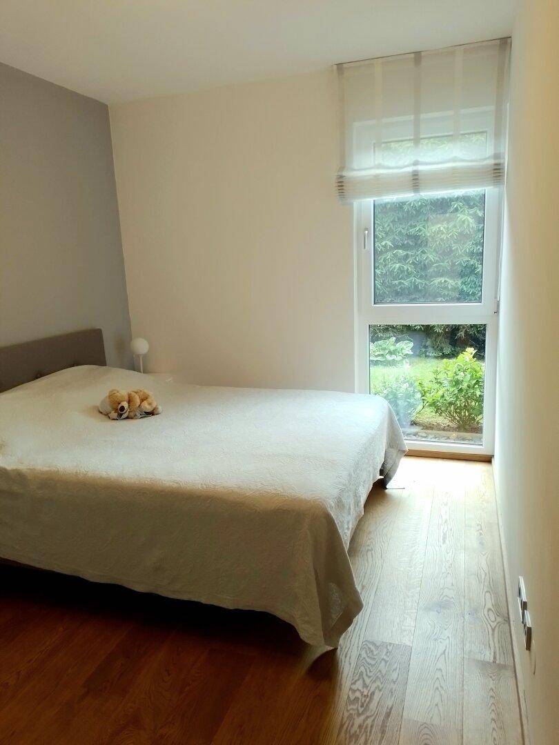 Schlafzimmer mit Doppelbett, Holzboden und Fenster mit Blick ins Grüne.