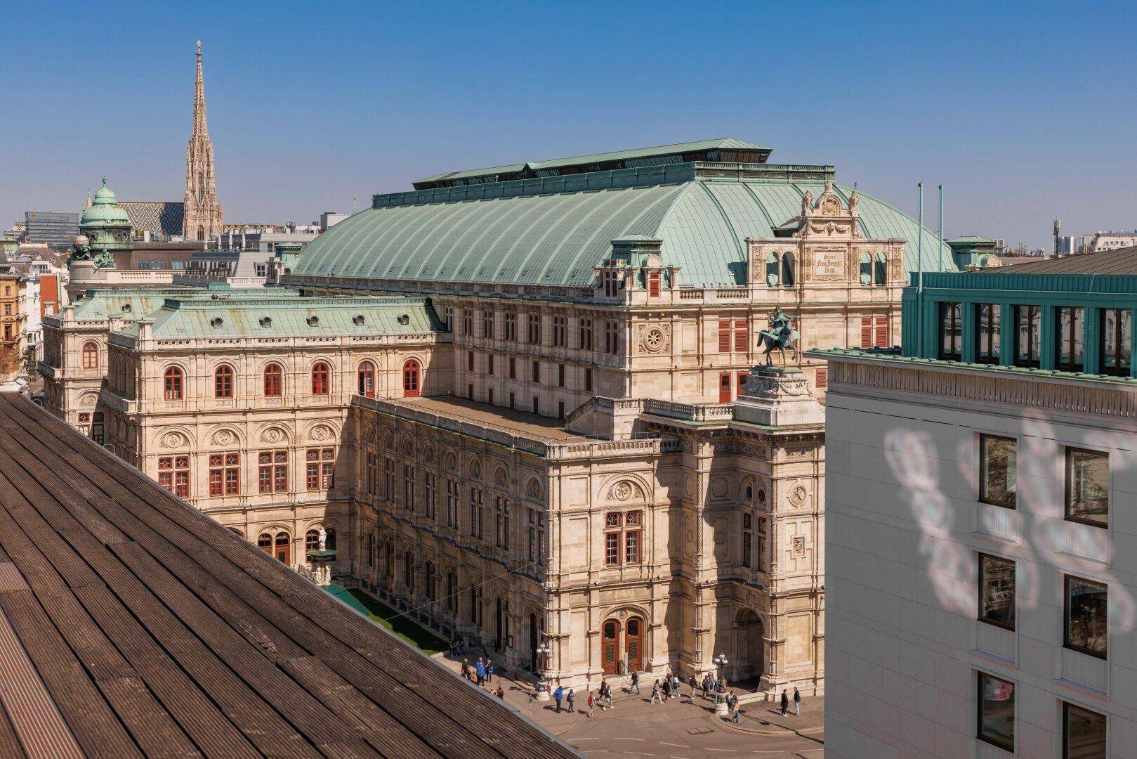 Historisches Gebäude mit markantem Dach und umliegender Stadtansicht.