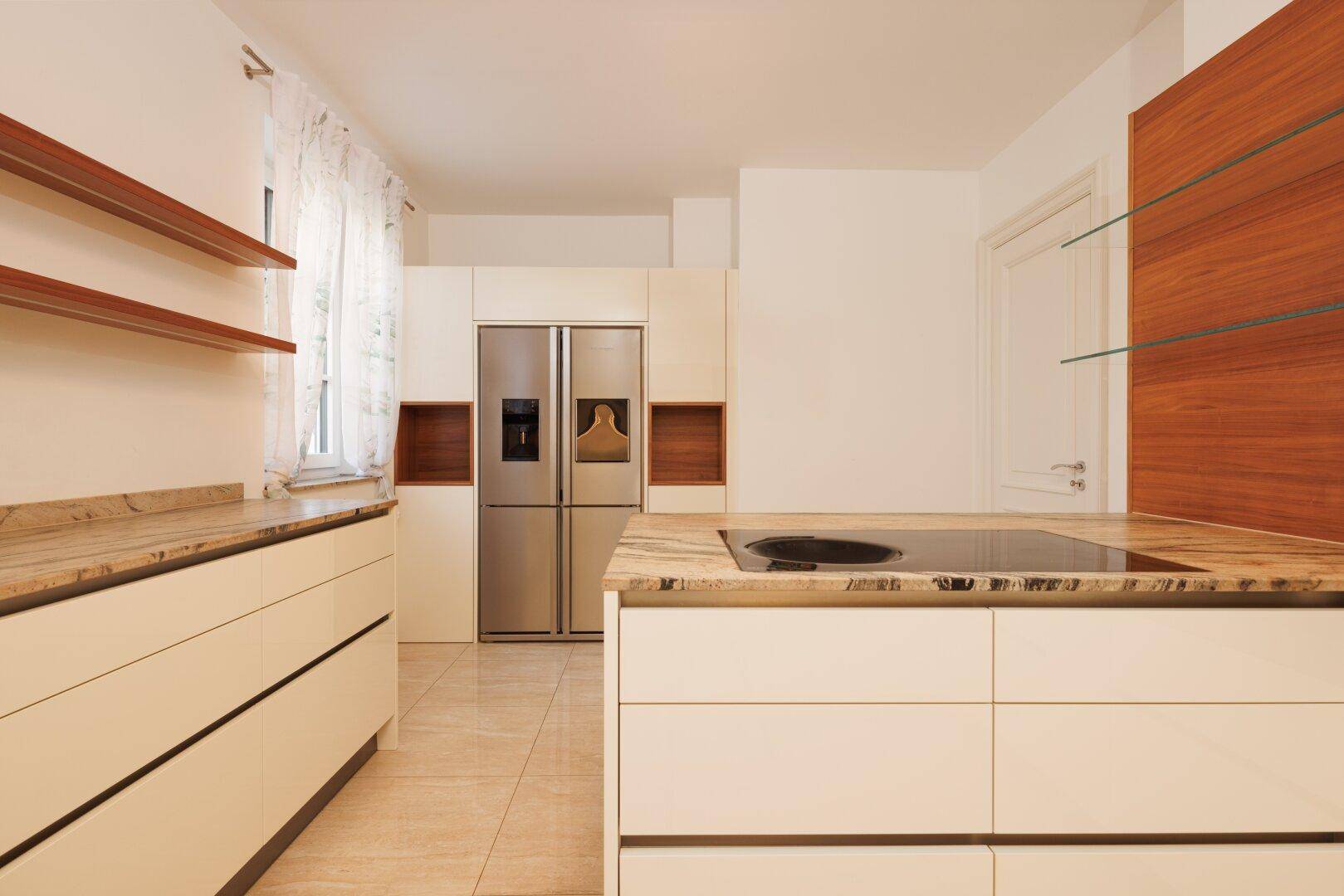 Moderne Küche mit Kochinsel, integriertem Kühlschrank und hellen Oberflächen, bietet viel Arbeitsfläche.