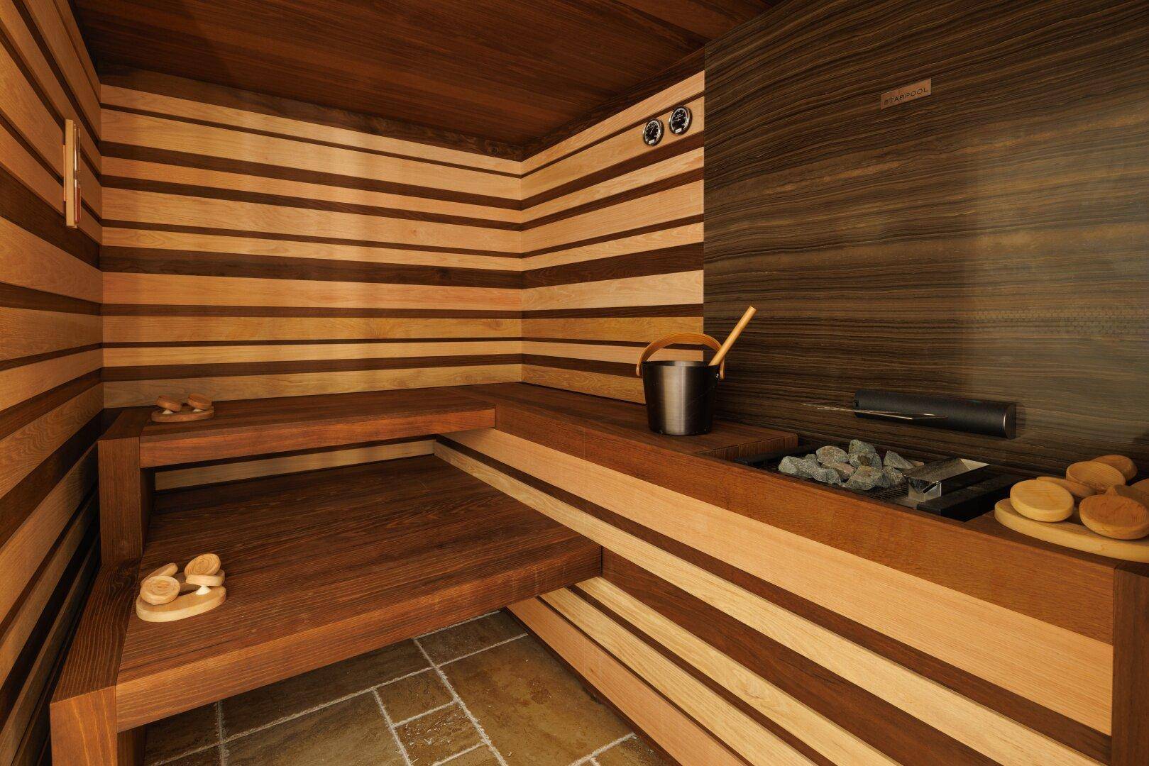 Moderne Sauna mit Holzbänken und Steinelementen, bietet Entspannung und Wohlbefinden.