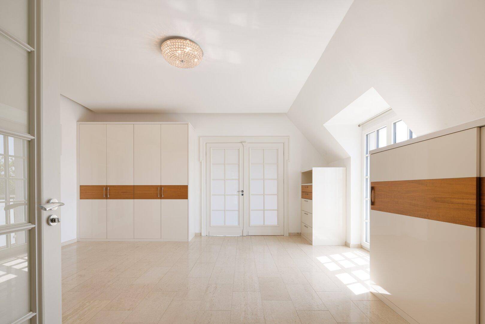 Geräumiges Schlafzimmer im Dachgeschoss mit Holzboden und Fenster, bietet eine angenehme Wohnatmosphäre.