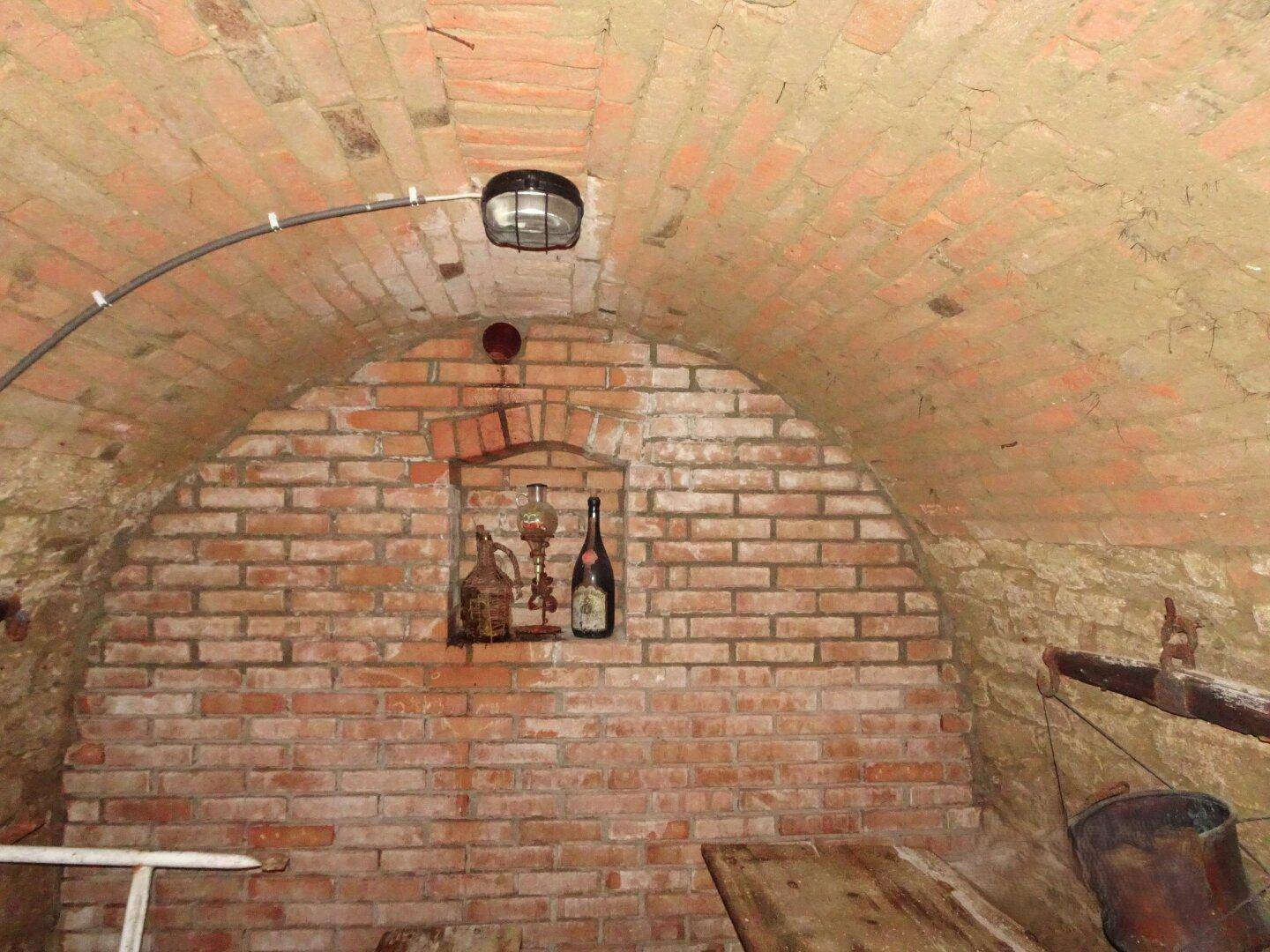 Historischer Gewölbekeller mit unverputzten Ziegelwänden und Nische für Weinflaschen, ideal zur Lagerung.