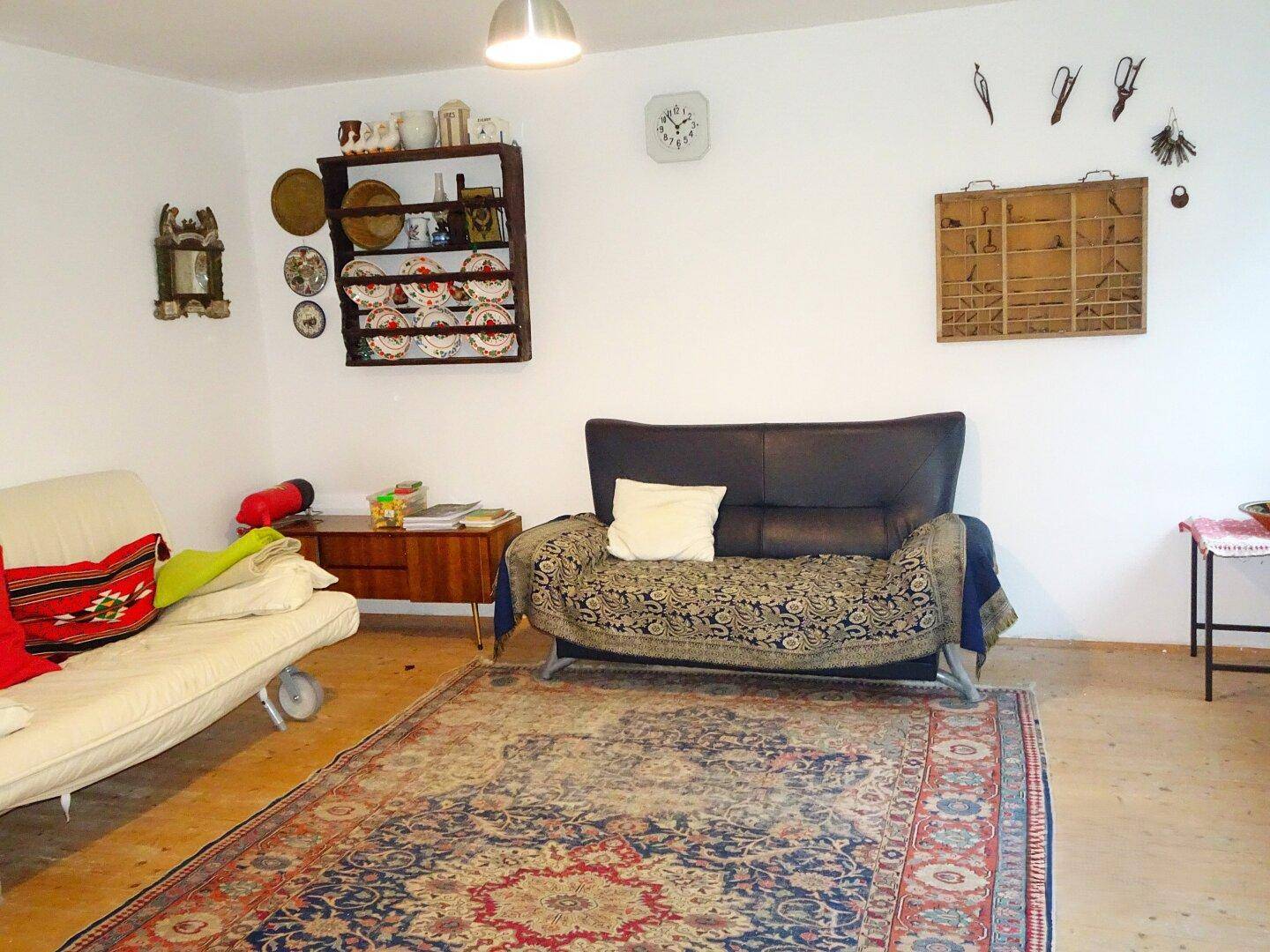 Helles Wohnzimmer mit zwei Sofas, Teppich und Holzboden, dekoriert mit traditionellen Elementen.