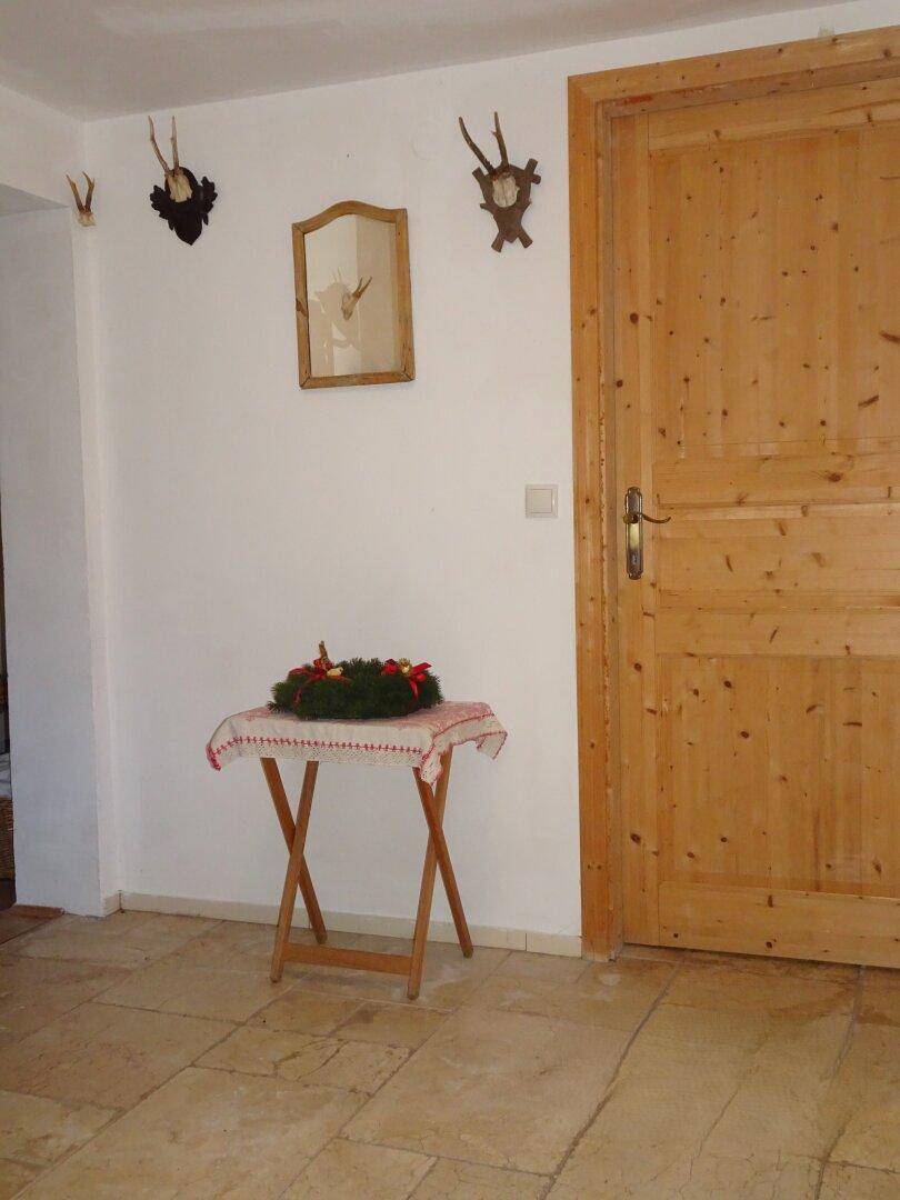 Eingangsbereich mit hellen Fliesen, Holztür und traditioneller Dekoration, die zum Landhausstil passt.