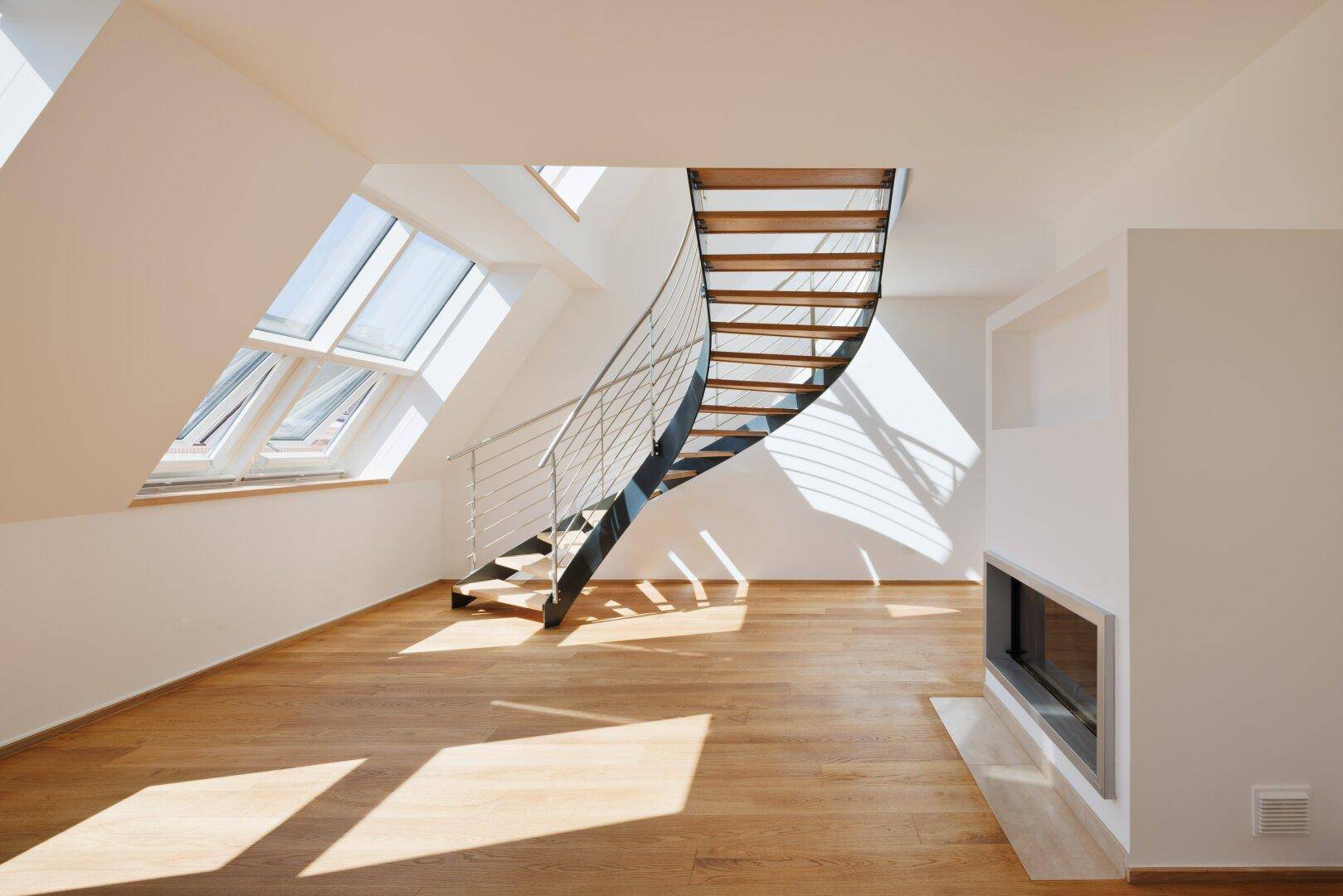 Geräumiger Wohnbereich mit Holzparkett, moderner Treppe und integriertem Kamin unter Dachfenstern.
