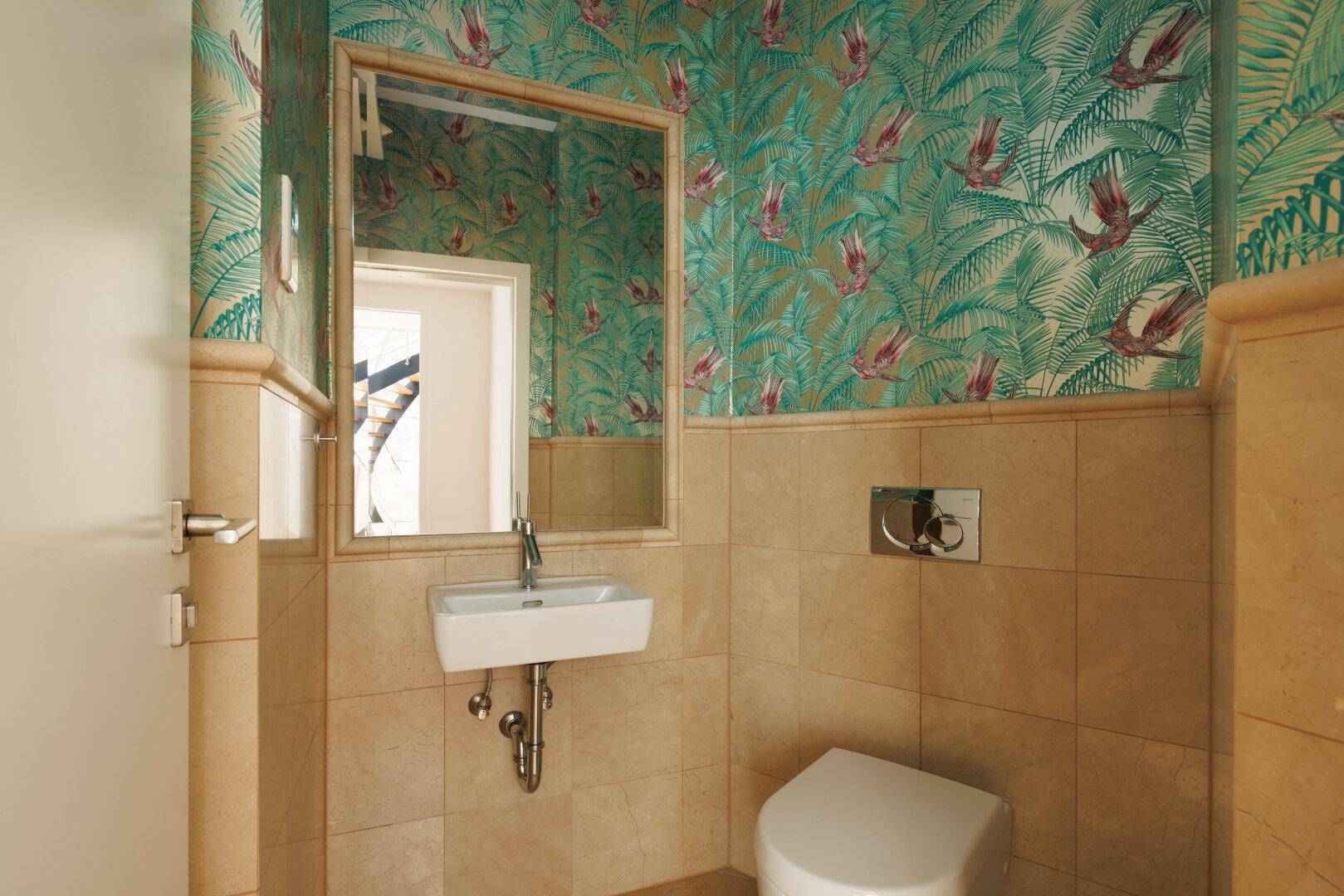 Stilvolles Gäste-WC mit gemusterten Tapeten, beigen Fliesen und modernem Waschbecken.