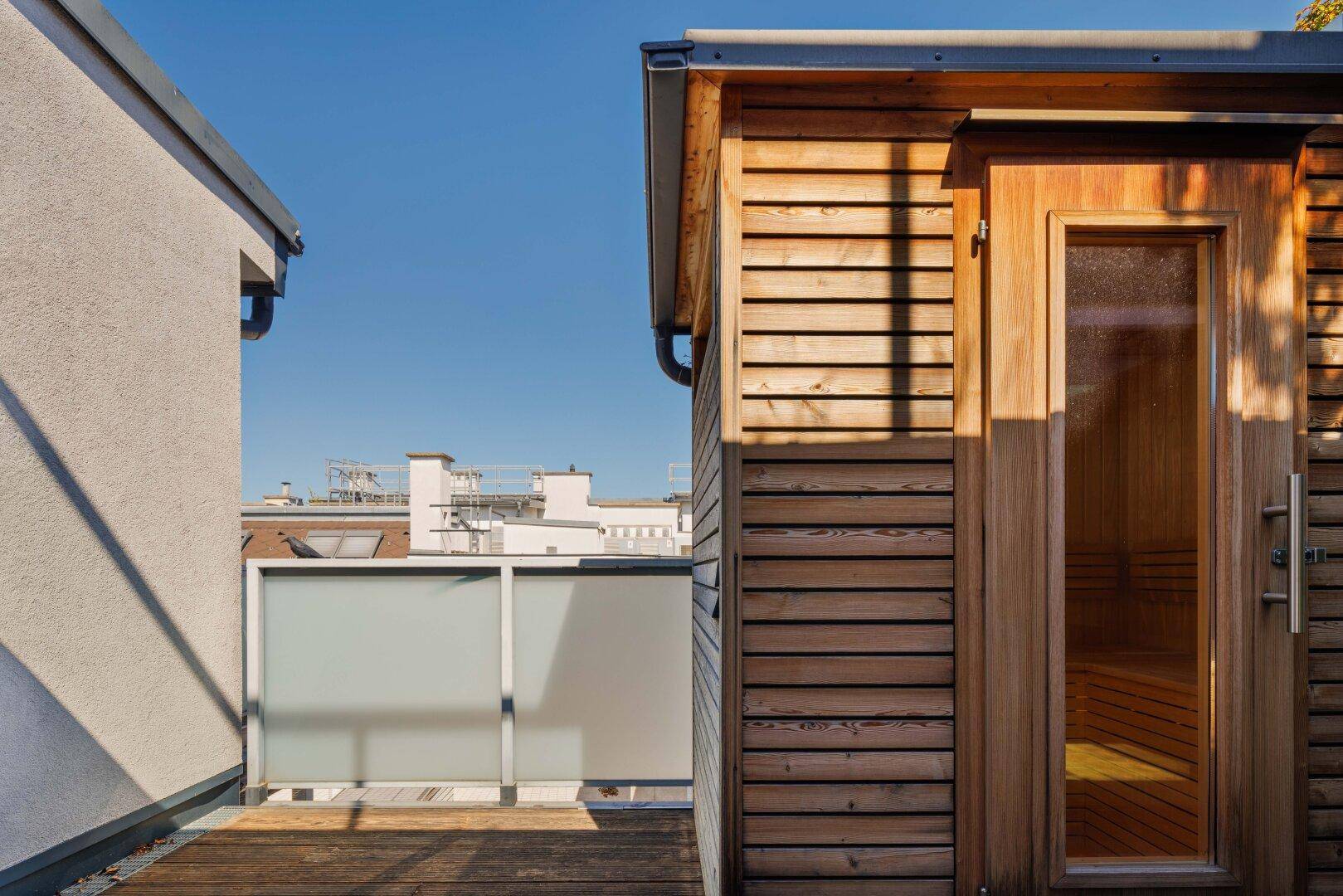 Externe Holzsauna auf einer Dachterrasse mit Blick über die Stadt.