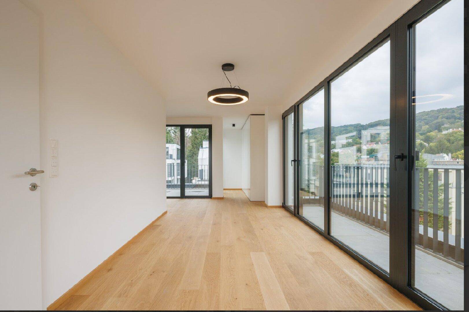 Lichtdurchfluteter Raum mit bodentiefen Fenstern und direktem Zugang zu einem Balkon.