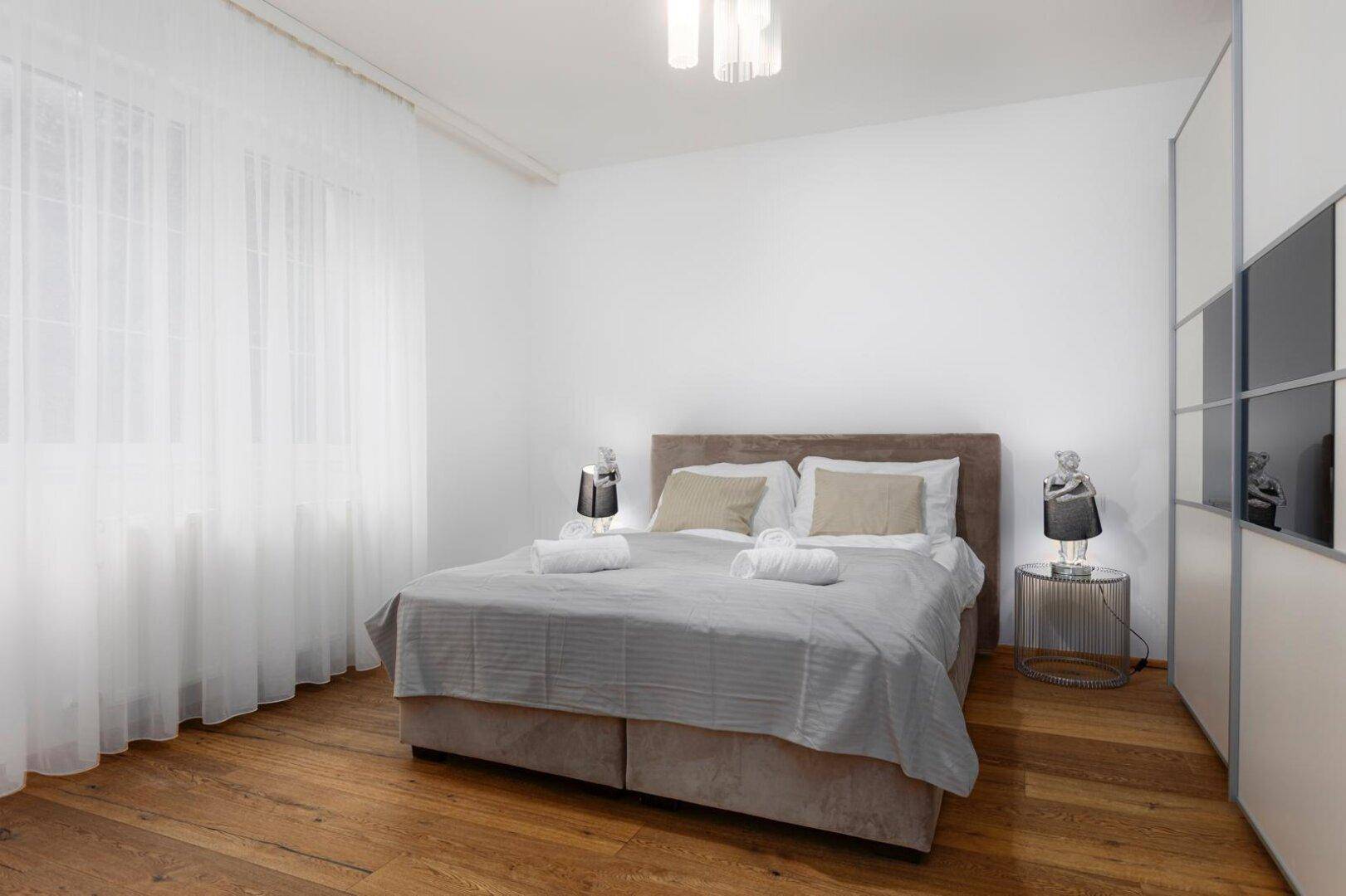 Helles Schlafzimmer mit Doppelbett, Holzboden und Einbauschrank, modern eingerichtet.